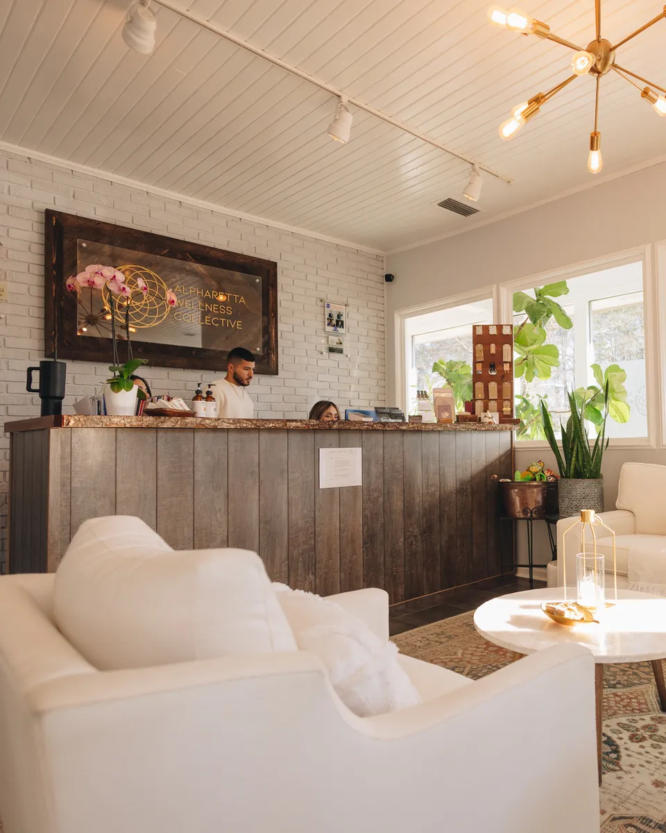 Reception: the front desk under the practice's sign on a white brick wall, with cream armchairs and a marble table in the waiting area.