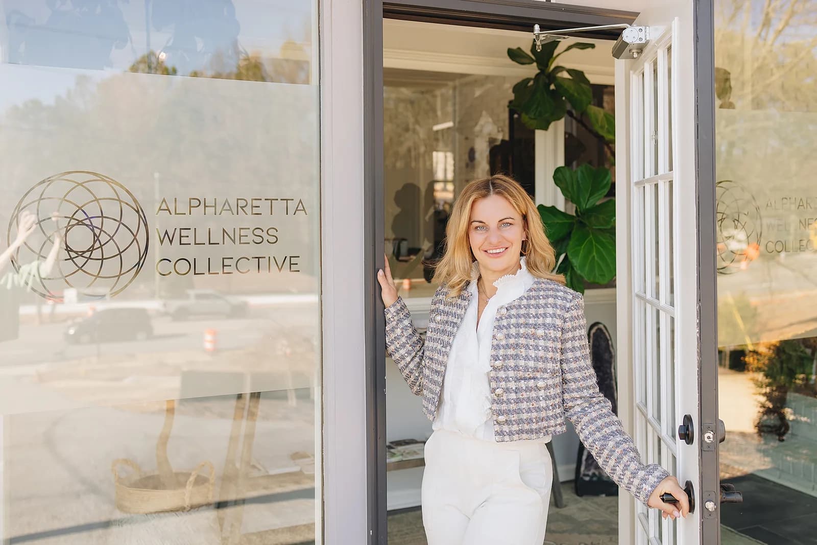The entrance held open, with the Alpharetta Wellness Collective mark etched into the glass.