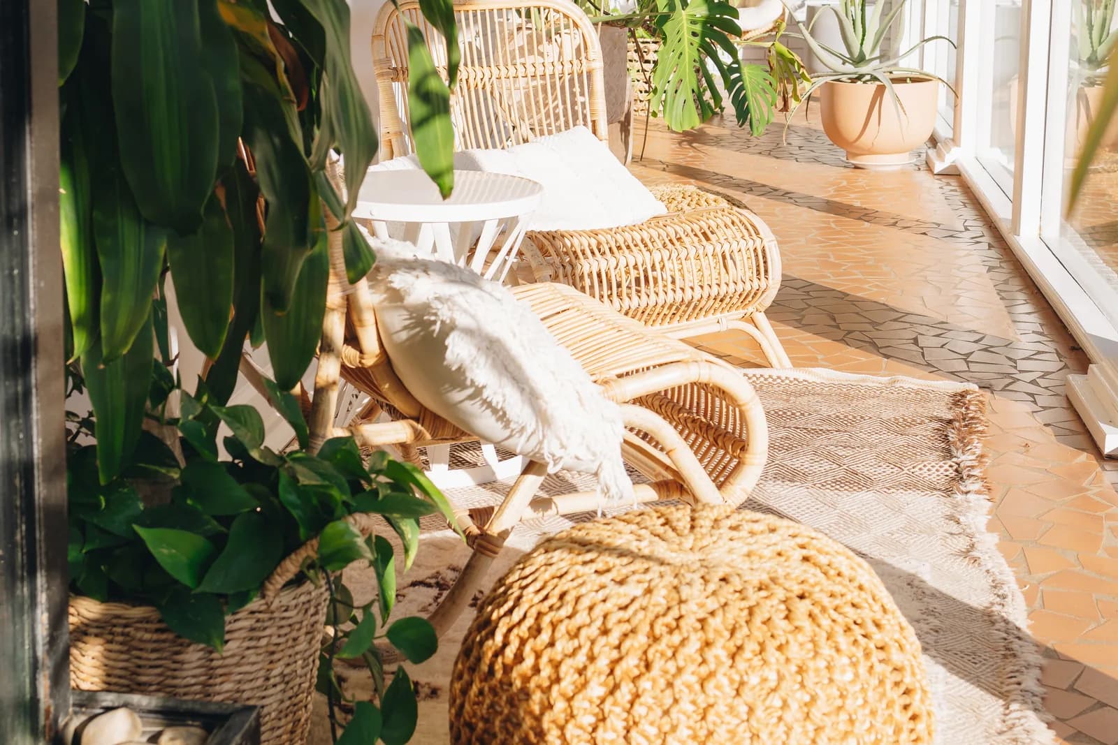 The sun porch inside the entrance, with rattan chairs and plants.