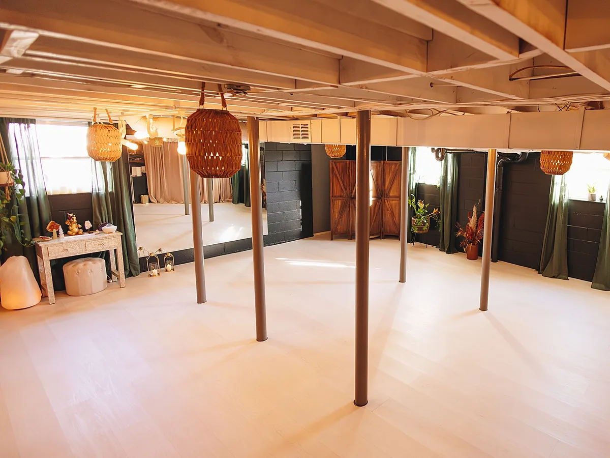 The Zen Den from the doorway: pale floor, grey support columns, woven lanterns and green curtains against dark painted walls.